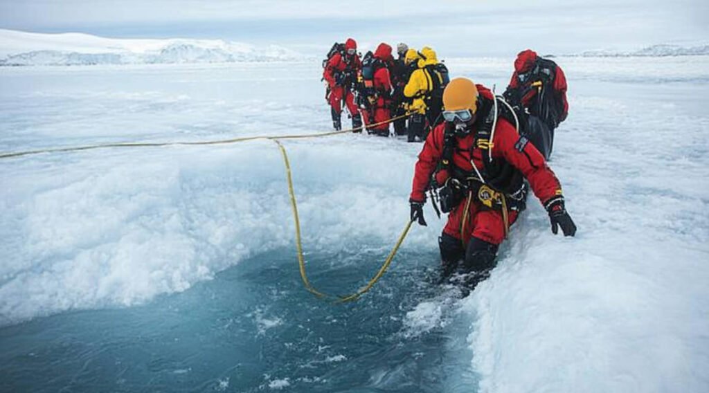 A diver ascending towards the entry hole in the ice, guided by a safety line, with a support team visible at the surface ready to assist.